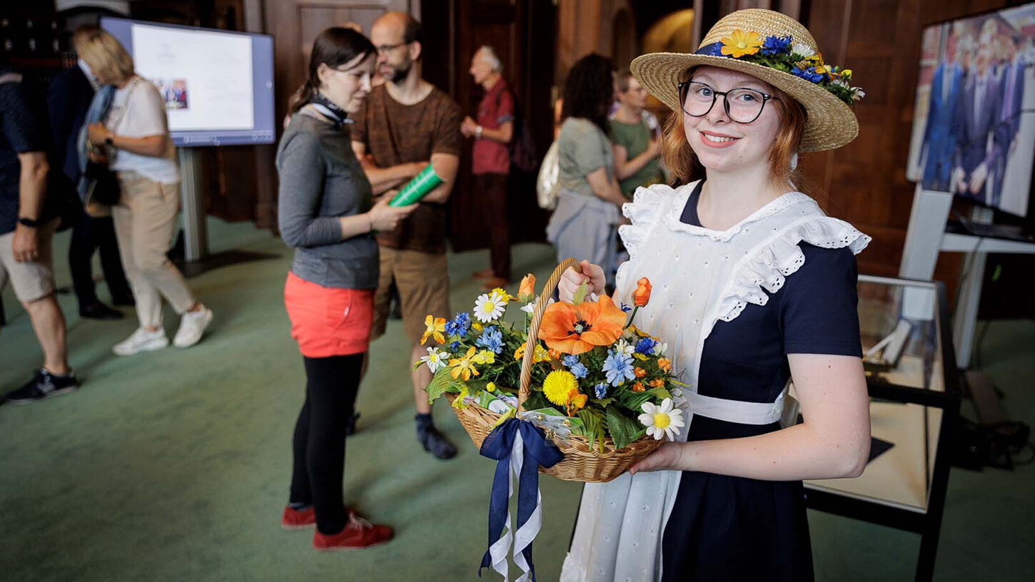 Ein Blumenmädchen steht in einem großen Saal.